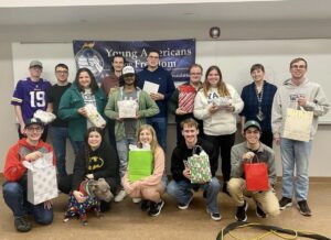 Group holding gift bags in front of banner.