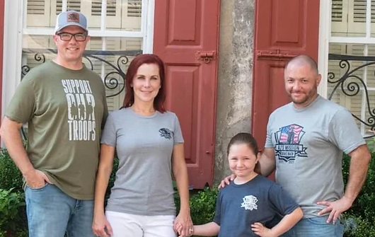 Family posing together outdoors smiling.