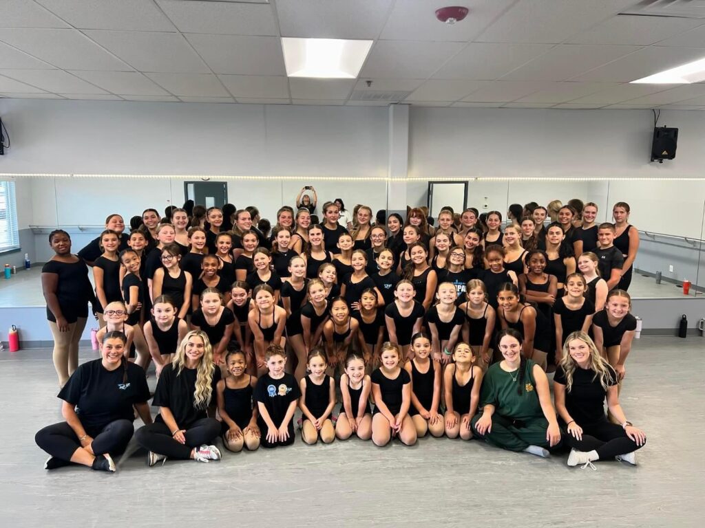 Large group of dancers posing in studio.